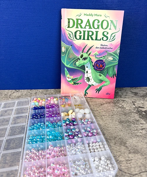 Foto mit den Gewinnspielpreisen: Das Buch Dragon Girls - Quinn, der Jadedrache (Band 6) und ein Perlen-Bastelset